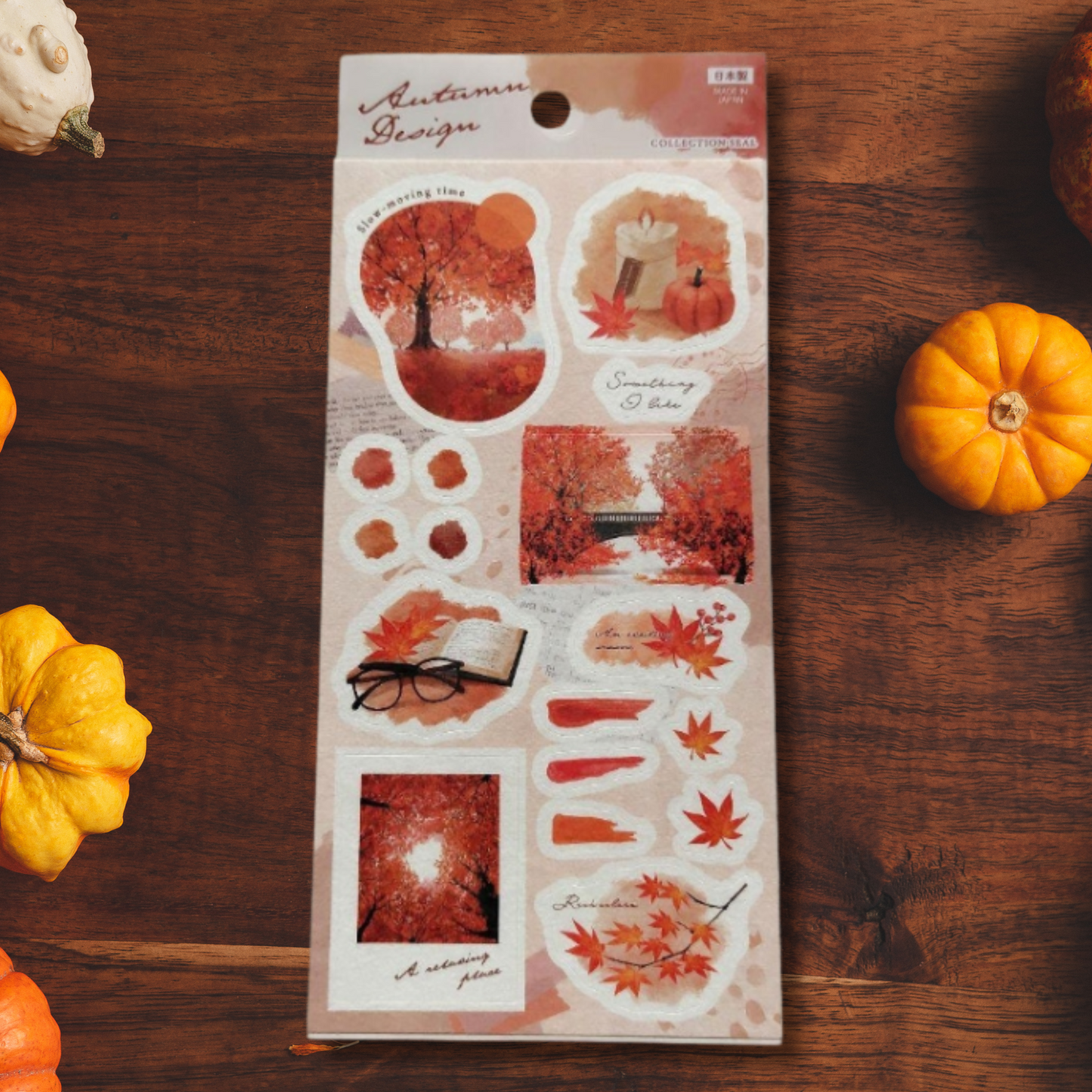 Set de pegatinas naranjas junto a accesorios de papelería y hojas secas, evocando la temporada otoñal.