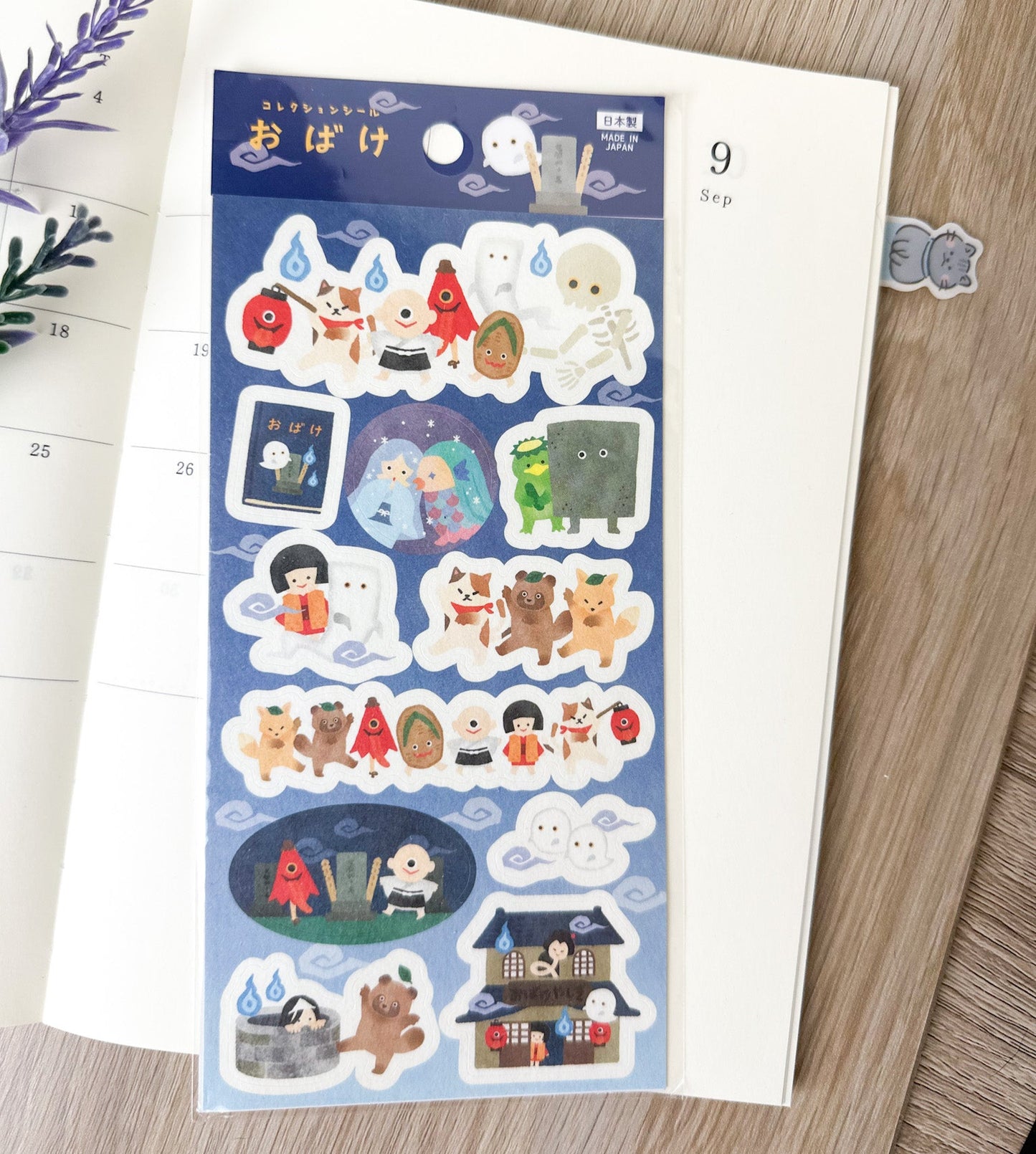Pegatinas japonesas con ilustraciones de fantasmas y criaturas yokai sobre una agenda abierta.