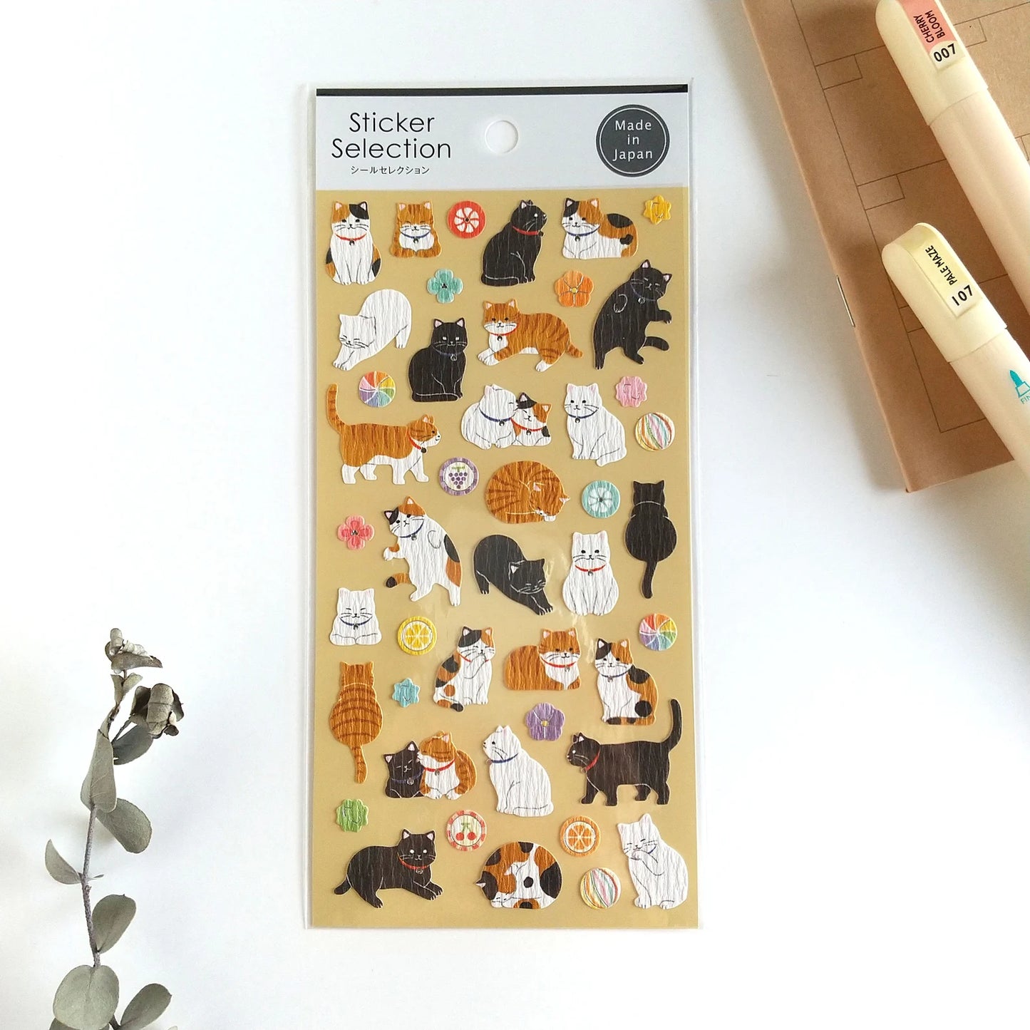 Pegatinas japonesas Gaia con ilustraciones de gatos blancos, negros y marrones jugando, sobre fondo beige.