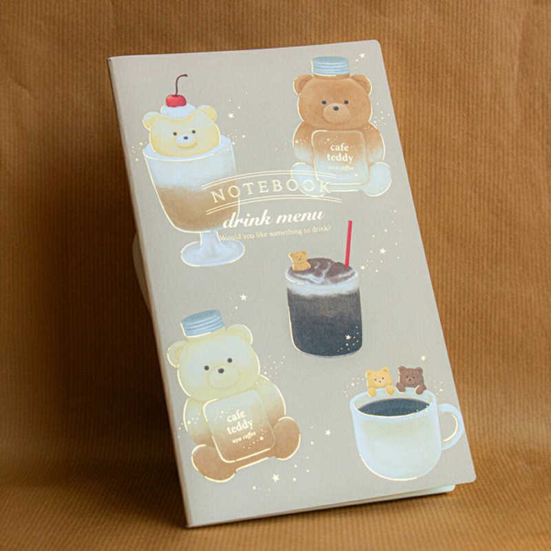 Primer plano de la libreta mostrando la ilustración de ositos en un ambiente de cafetería, con detalles cálidos que transmiten ternura