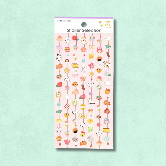 Lámina de pegatinas japonesas de Gaia con pequeños colgantes decorativos inspirados en festividades, dulces y amuletos tradicionales, en tonos alegres y detalles delicados.