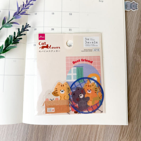 Pegatinas japonesas con gatitos kawaii, sobre agenda abierta con decoración floral.