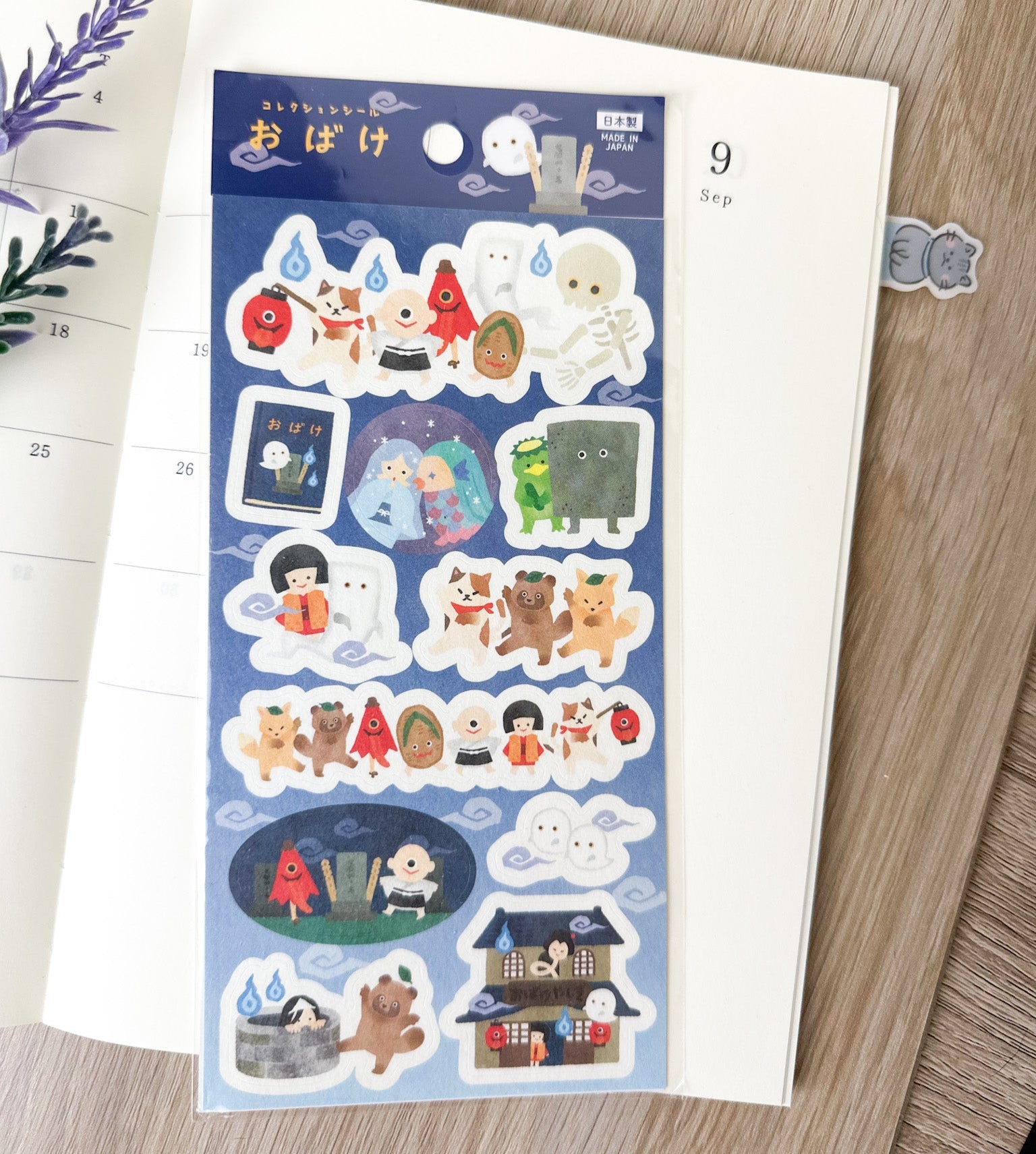 Pegatinas japonesas con ilustraciones de fantasmas y criaturas yokai sobre una agenda abierta.
